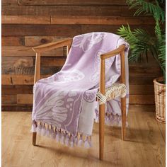 a chair with a purple blanket on top of it next to a potted plant