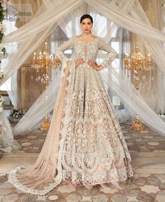 a woman standing in front of a chandelier wearing a white and gold gown