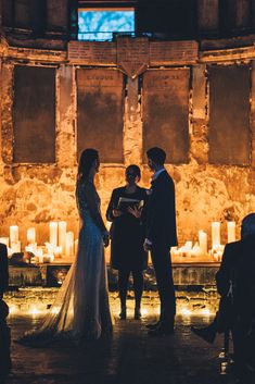 a bride and groom standing at the alter during their wedding ceremony in front of candles