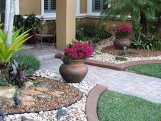 a house with landscaping in front of it and flowers on the ground next to it