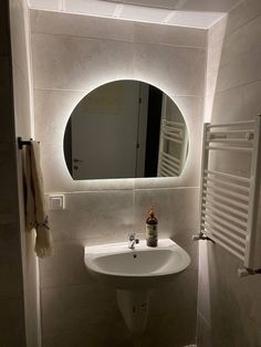 a white sink sitting under a bathroom mirror next to a towel dispenser