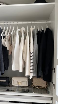 an organized closet with clothes and handbags hanging on the rail, including sweaters