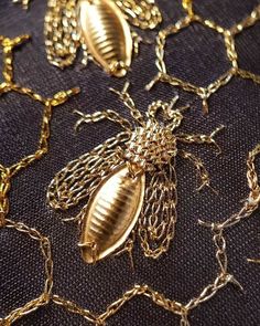 some gold chains are on top of a black cloth with a bee motif in the middle