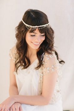 a woman in a white dress is wearing a head piece with pearls and beads on it