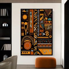 an orange and black abstract painting hangs on the wall above a chair in front of a bookshelf