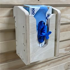 a blue tie hanging from the side of a wooden box on a wood paneled wall