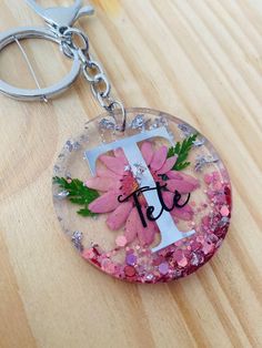 a glass keychain with pink flowers and the letter f on it's side