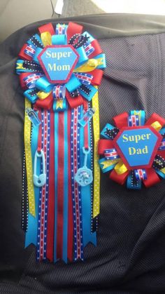 two ribbons are attached to the back of a car's seat belt, and one has a badge that says super dad on it