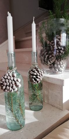 two glass bottles filled with pine cones and candles