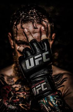 a close up of a person with tattoos on their arms and hands wearing boxing gloves