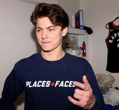 a young man in a blue sweatshirt holding his thumb up