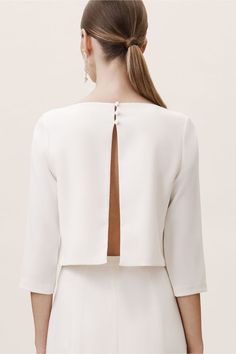 the back of a woman's white dress with a cutout at the neck