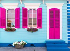 a blue house with pink shutters and flower boxes on the front door is shown