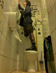 a man standing on top of a toilet in a bathroom