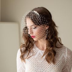 a woman wearing a birdcage veil over her head