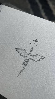 a drawing of a bat on paper with stars in the sky above it and an ink pen