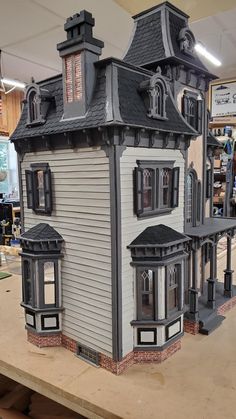 a doll house is on display in a store with lots of windows and shingles