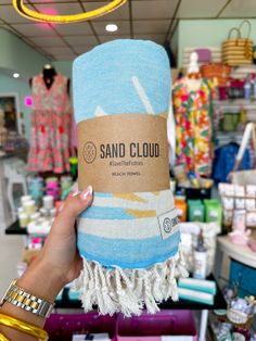 a person holding up a blue towel in a store with other items on the shelves