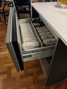 an open drawer in the middle of a kitchen counter with several cans of beer on it