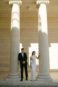 a man and woman standing next to each other in front of pillars