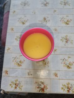 a pink cup filled with orange juice on top of a table