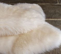 a white sheepskin rug laying on top of a wooden floor next to a brick wall