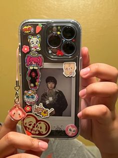 a person holding up a cell phone case with stickers on the front and sides