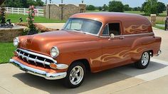 an orange truck with flames painted on it's side parked in front of a brick building