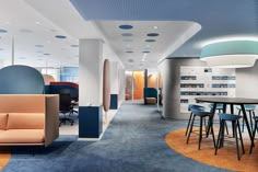 an office with blue and orange carpeting, white walls, and round seating areas