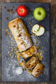 an apple and cinnamon roll on a slate board