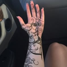 a woman's hand with tattoos on it sitting in the passenger seat of a car