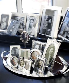 a tray with pictures and frames on it sitting on a table in front of a mirror