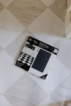 a package of white and black tile sitting on top of a checkerboard floor