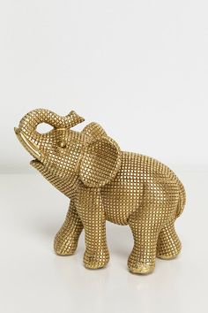 an elephant figurine is shown on a white surface and has gold colored metal mesh covering it's body