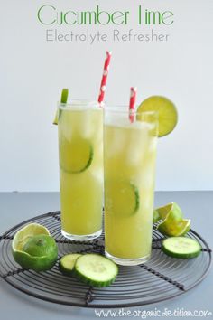 two glasses filled with lemonade and cucumber limes on a cooling rack