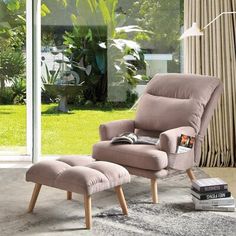 a living room with a chair, ottoman and book on the floor in front of a sliding glass door