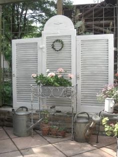 an outdoor garden area with potted plants and watering cans on the side of it