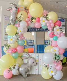 a balloon arch is decorated with pastel colors and balloons in the shape of animals