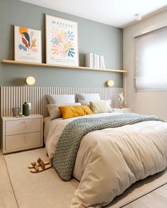 a bedroom with a bed, nightstands and two pictures on the wall above it