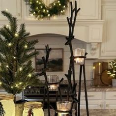 candles are sitting on the counter in front of a christmas tree and candle holders with lights