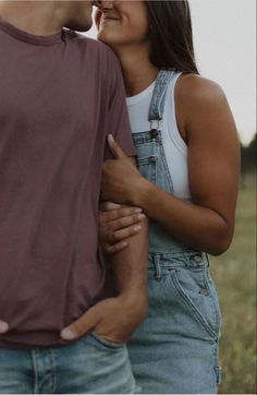 a man and woman standing next to each other with their hands on the back of their backs