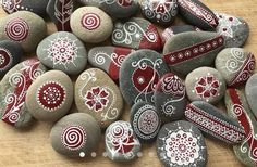 some rocks with designs on them sitting on a wooden table and one has a cell phone in it