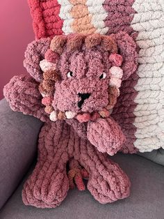 a crocheted stuffed animal sitting on top of a couch next to a pillow