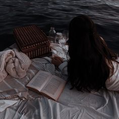 a woman laying on top of a bed next to an open book and bottle of water