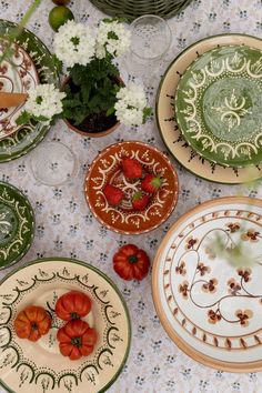 there are many plates on the table that have flowers in them and one has strawberries