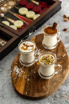 three cups filled with different kinds of food on top of a wooden tray next to an assortment of desserts