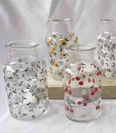 five glass vases with flowers and berries on them