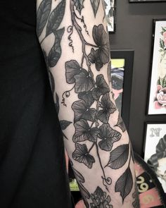 a woman's arm with flowers and leaves on it