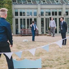 several men in suits and ties are playing frisbee on the grass near a building