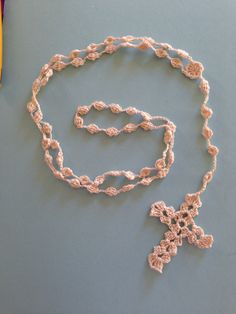 a crocheted necklace is laying on a table next to a pen and pencil